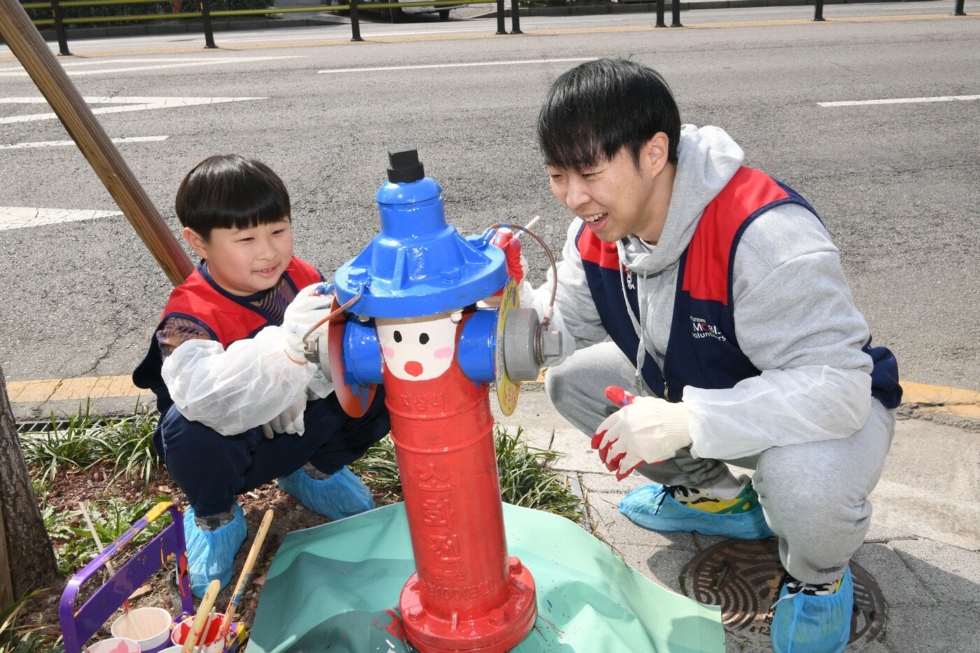 본문 이미지 - 현대모비스 임직원들이 자녀들과 함께 수도권 일대에서 소화전 도색 활동을 펼치는 모습. 2024년 시작한 소화전 도색 활동으로 올해까지 누적 1000개의 소화전이 새단장될 예정이다(현대모비스 제공). 2026.7.16.