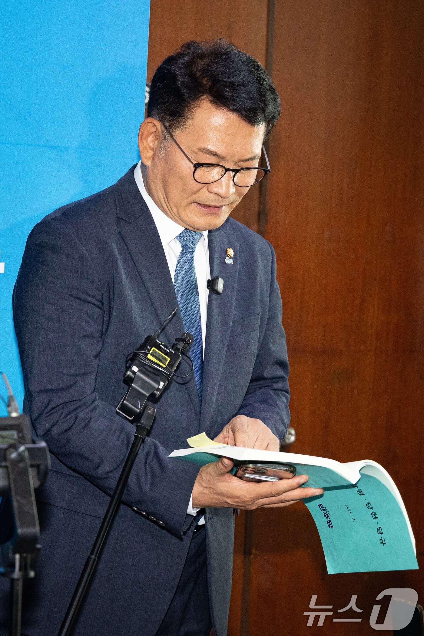본문 이미지 - 더불어민주당 8·17 전당대회에서 당대표에 출마하려다 '피선거권 자격 논란'에 휩싸인 송영길 전 대표가 17일 서울 여의도 국회에서 열린 비공개 최고위원회의에 참석 후 기자회견 중 당헌·당규집을 살피고 있다. 2026.7.17 ⓒ 뉴스1 유승관 기자