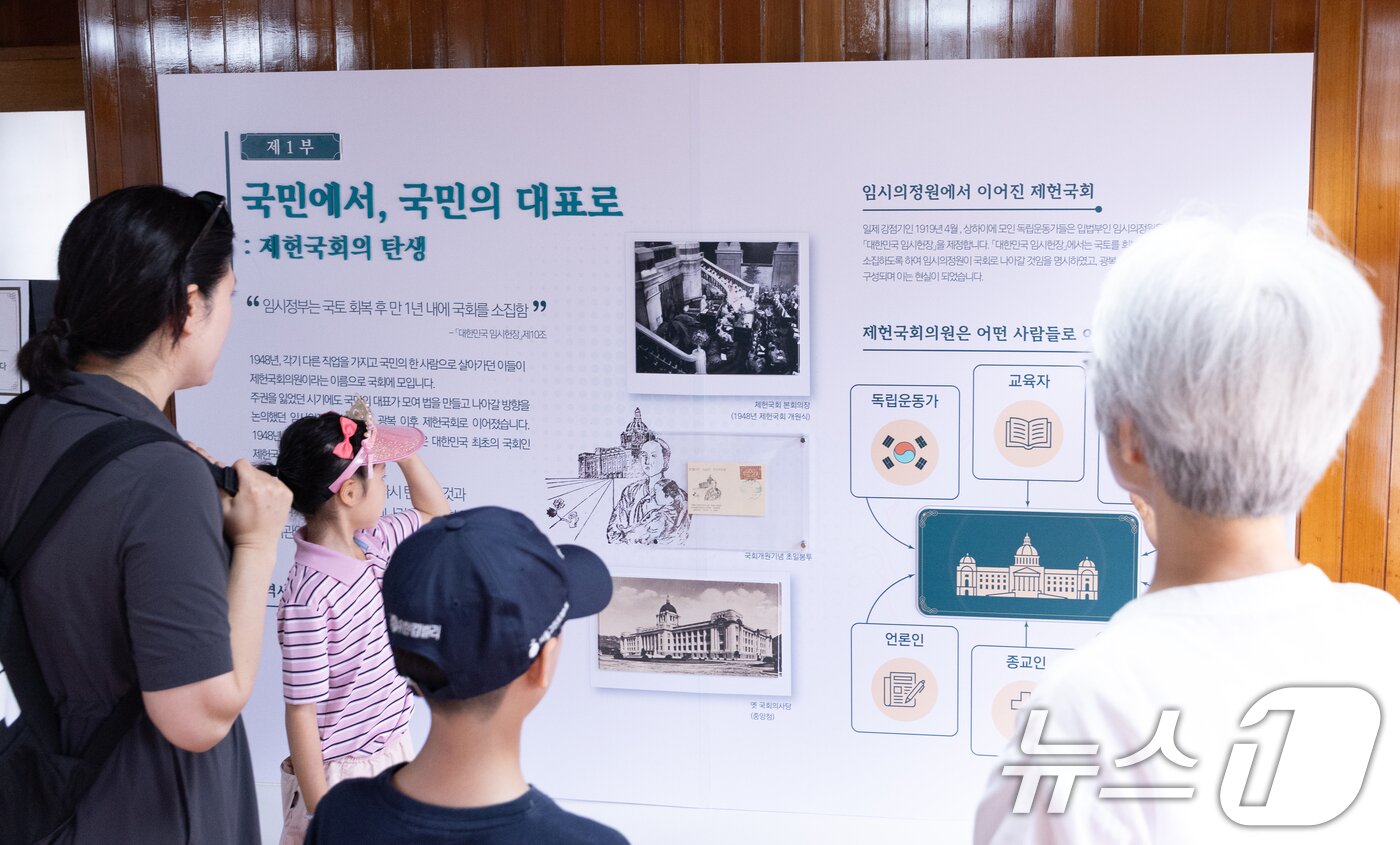 본문 이미지 - 대한민국 헌법의 제정을 기념하고 의미를 되새기는 제78회 '제헌절'인 17일 서울 종로구 제헌국회전시관(제헌회관)을 찾은 가족이 제헌국회에 대한 설명을 들으며 전시를 관람하고 있다. 2026.7.17 ⓒ 뉴스1 안은나 기자