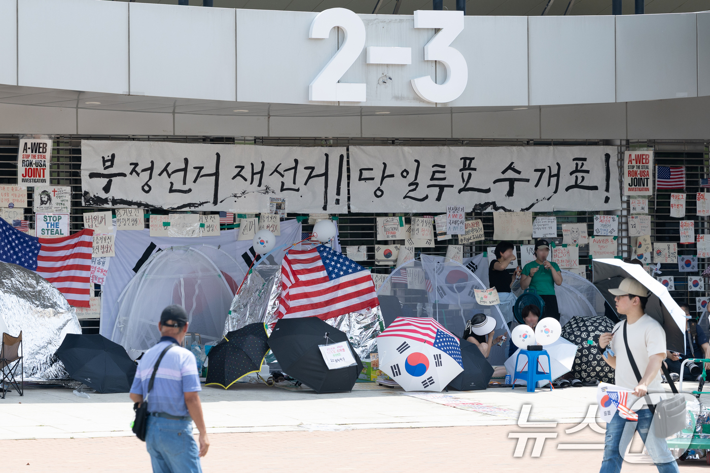 (서울=뉴스1) 안은나 기자 = 6·3지방선거 이후 한 달 넘게 개표소 봉쇄 시위가 계속되고 있는 17일 서울 송파구 올림픽공원 핸드볼경기장 입구 앞을 시민들이 지나고 있다. 20 …