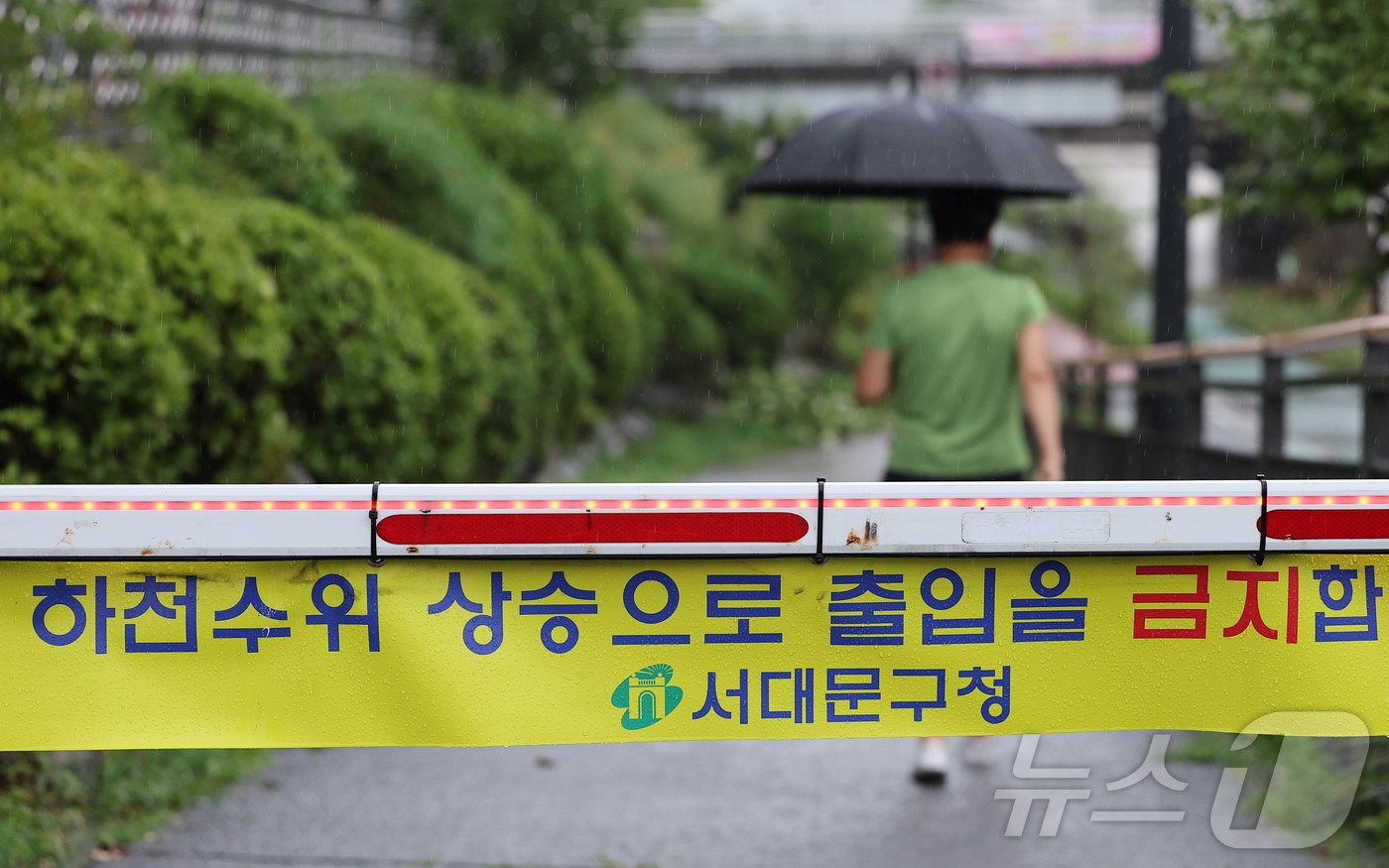 (서울=뉴스1) 김성진 기자 = 새벽부터 수도권에 집중호우가 내린 18일 한 시민이 출입 통제된 서울 은평구 불광천 산책로를 들어서고 있다. 2026.7.18/뉴스1