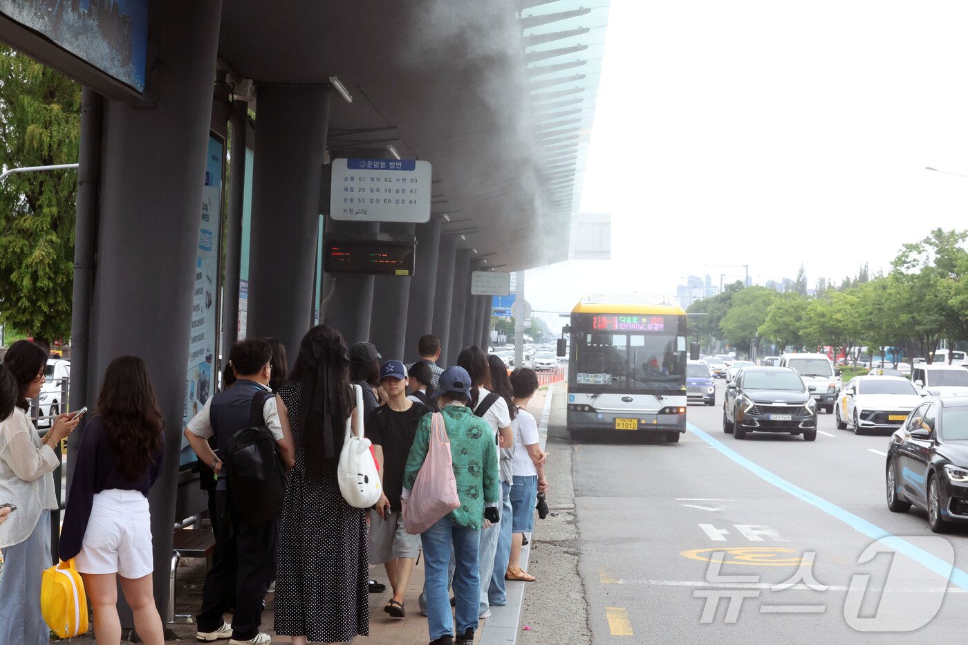 본문 이미지 - 18일 오후 전남광주통합특별시 서구 광천동 광주종합버스터미널 버스정류장을 찾은 시민들이 쿨링포그 아래에서 버스를 기다리고 있다. 2026.7.18 ⓒ 뉴스1 조수민 기자
