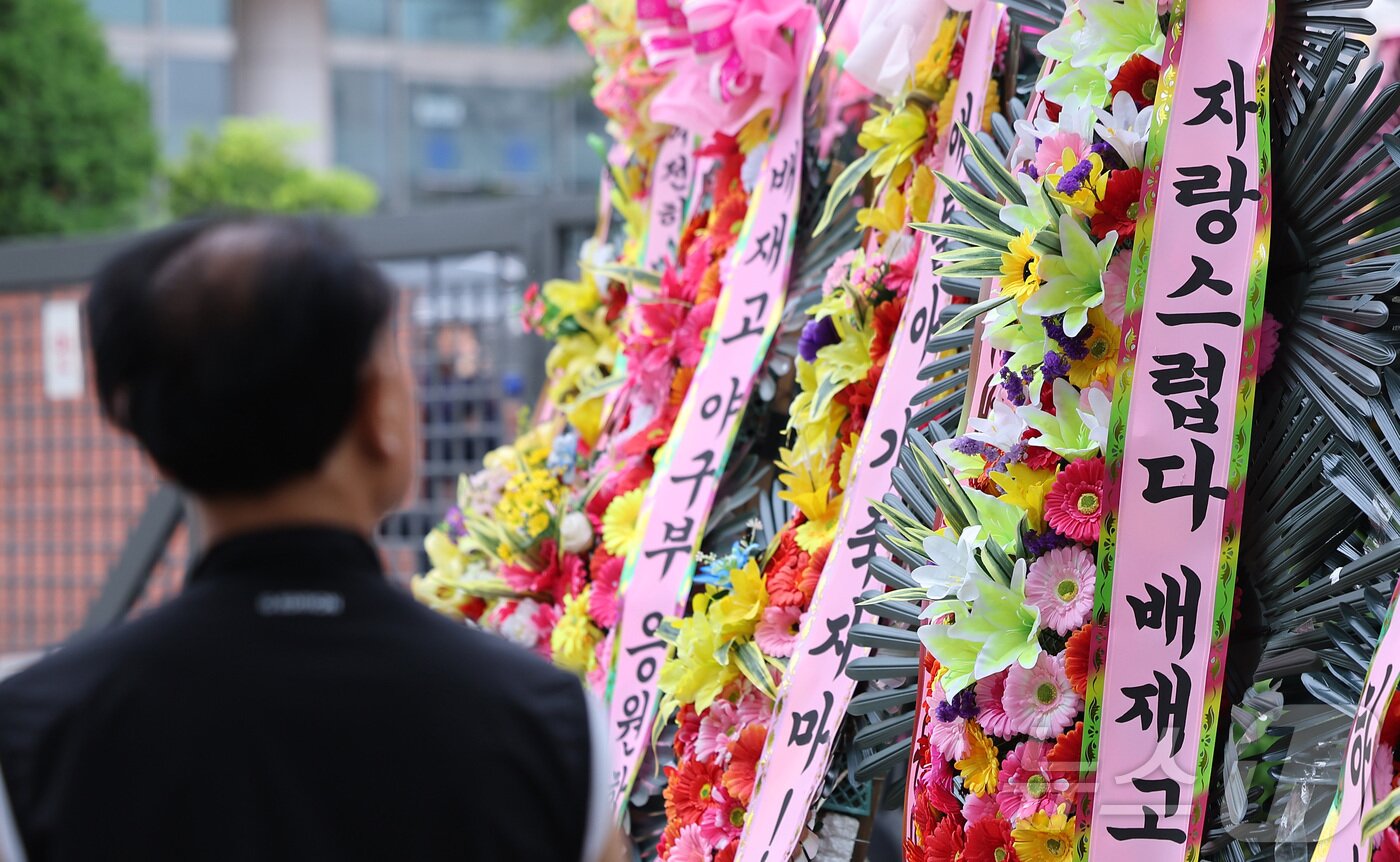 본문 이미지 - 2일 서울 강동구 배재고등학교 앞에 배재고등학교 야구부를 응원하는 화환이 놓여 있다. 앞서 배재고 선수들은 지난달 29일 서울 목동구장에서 열린 제81회 청룡기 전국고교야구선수권대회에서 상대 팀인 광주제일고를 향해 "스타벅스 가야지＂, ＂탱크데이＂ 등의 구호를 외쳐 논란이 됐다. 이에 대한야구소프트볼협회는 전날 스포츠공정위원회를 열고 배재고 야구부에 전국대회 출전 정지 6개월 중징계를 내렸다. 2026.7.2 ⓒ 뉴스1 김성진 기자