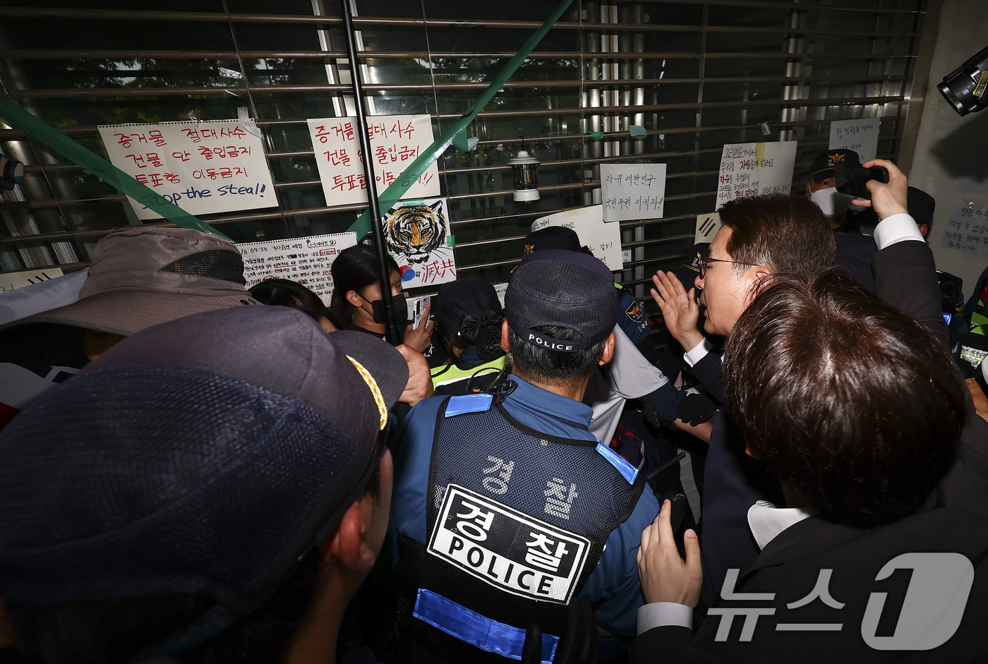 (서울=뉴스1) 국회사진기자단 = 신동욱 국민의힘 의원이 2일 서울 송파구 올림픽공원 내 개표소 앞에서 문을 가로막은 시위 참가자와 이야기를 하고 있다. 2026.7.2/뉴스1