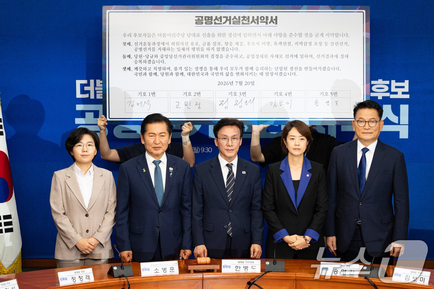 본문 이미지 - 더불어민주당 8·17 전당대회 당대표 후보들이 20일 서울 여의도 국회에서 열린 공명선거 실천 서약식에서 서약서에 서명 후 기념 촬영을 하고 있다. 왼쪽부터 김보미, 정청래, 김민석, 고민정, 송영길 후보. 2026.7.20 ⓒ 뉴스1 유승관 기자