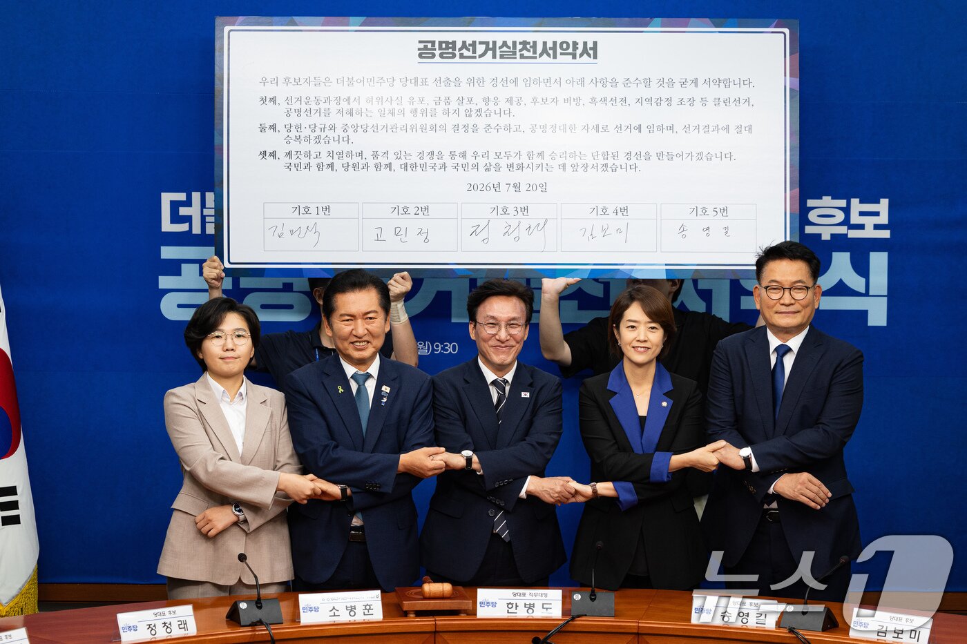 본문 이미지 - 더불어민주당 8·17 전당대회 당대표 후보들이 20일 서울 여의도 국회에서 열린 공명선거 실천 서약식에서 서약서에 서명 후 기념 촬영을 하고 있다. 2026.7.20 ⓒ 뉴스1 유승관 기자