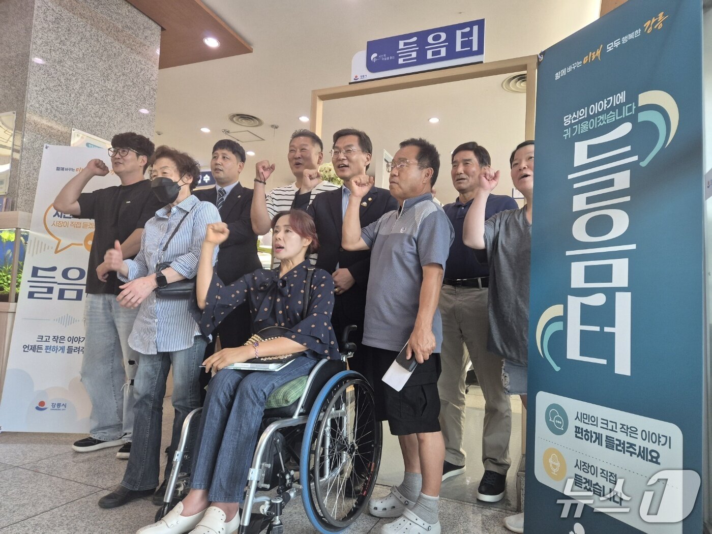 본문 이미지 - 김중남 강릉시장(사진 가운데)이 21일 시청 1층 시민 소통공간 '들음터' 개소를 기념하며 첫 날 민원인들과 함께 파이팅을 외치고 있다. 2026.7.21/뉴스1 윤왕근 기자