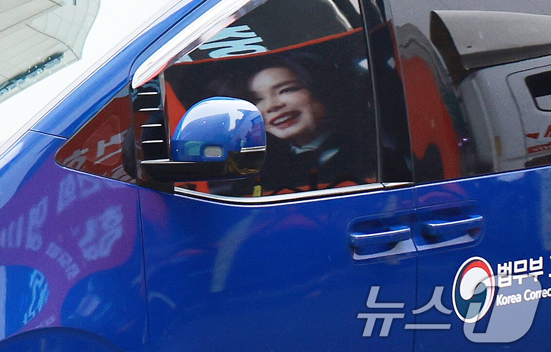 본문 이미지 - 김건희 여사를 태운 호송차가 22일 경기 과천 2차 종합특검 사무실 지하주차장으로 들어서고 있다. 김여사가 탄 차량에 지지자들이 걸은 김여사 사진이 비춰지고 있다. 2차 종합특검팀(특별검사 권창영)은 이날 윤석열 전 대통령 관저 이전과 관련 특정범죄가중처벌법상 알선수재와 직권남용 혐의로 김 여사를 피의자 신분으로 소환했다. 2026.7.22 ⓒ 뉴스1 이호윤 기자