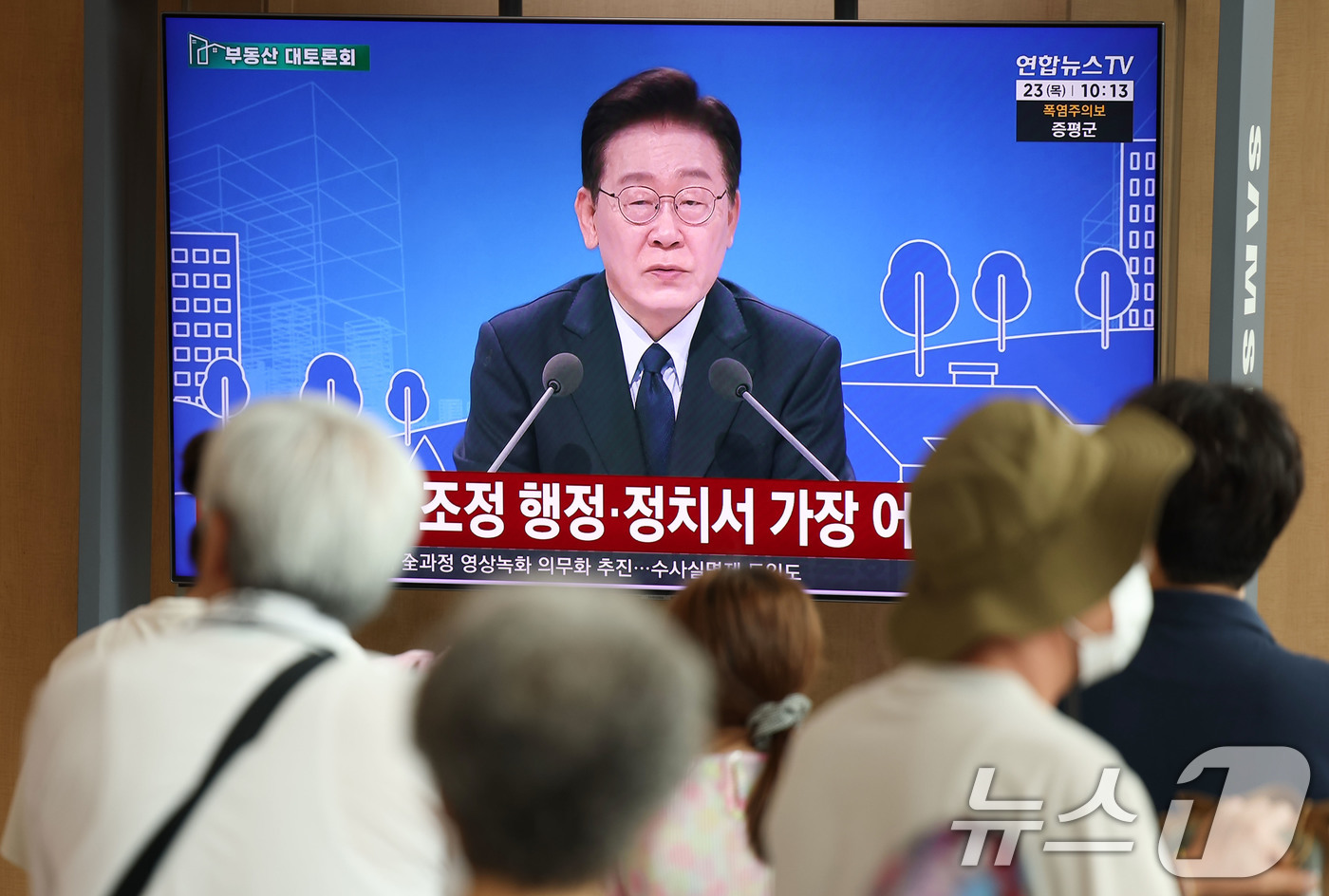 (서울=뉴스1) 이종수 기자 = 23일 오전 서울역 대합실에서 시민들이 이재명 대통령이 주재하는 부동산 대토론회 TV 생중계를 시청하고 있다. 2026.7.23/뉴스1