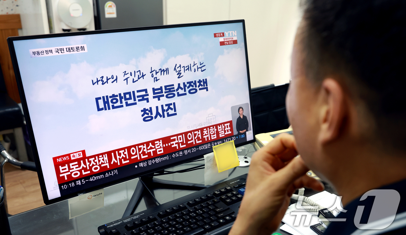 (서울=뉴스1) 이호윤 기자 = 이재명 정부의 부동산 정책 국민 대토론회가 개최된 23일 서울시내의 한 부동산에서 공인중개사가 토론회 생방송을 시청하고 있다. 2026.7.23/뉴 …