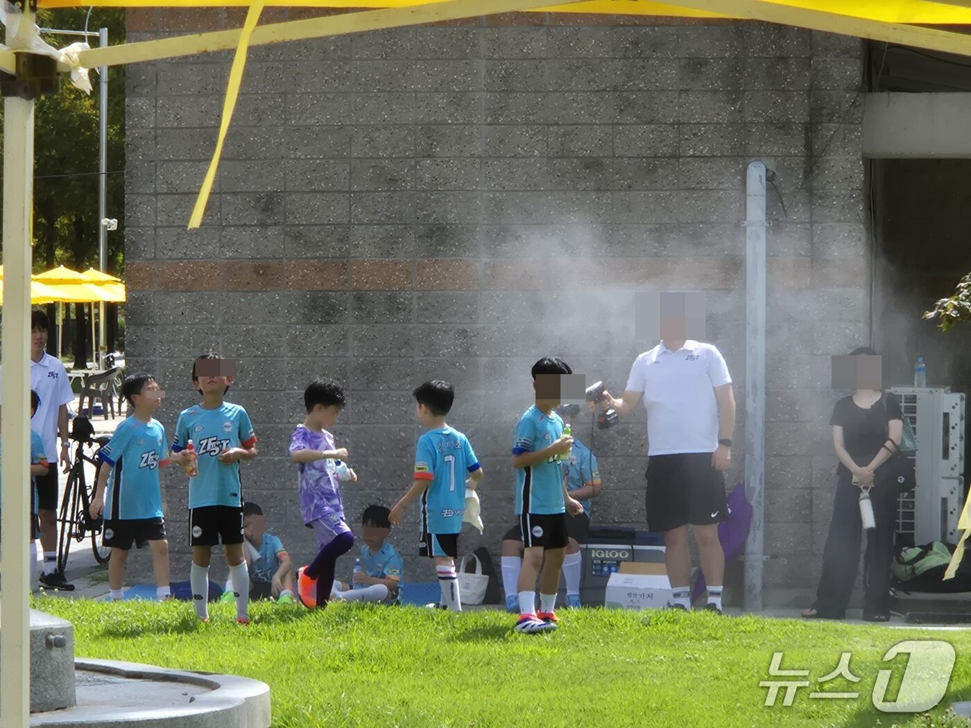 본문 이미지 - 25일 전주시 월드컵경기장 물놀이장 옆 풋살 축구장에서 관계자가 물 분부기로 아이들의 체온을 낮추고 있다./뉴스1  