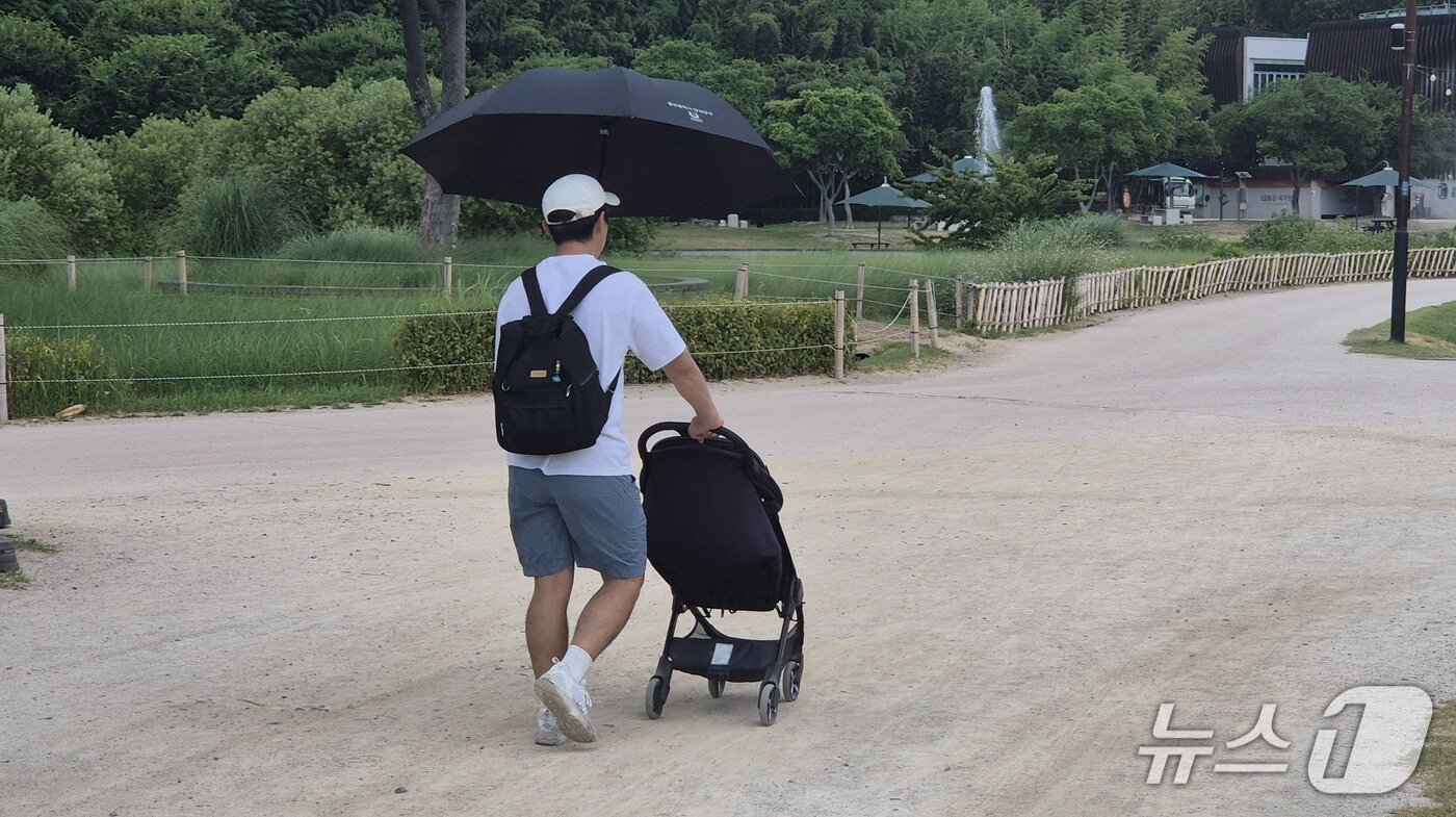 본문 이미지 - 26일 오전 11시 30분 울산 태화강국가정원에서 한 시민이 양산을 쓴 채 자녀와 함께 산책하고 있다. 2026.7.26 ⓒ 뉴스1 박정현 기자
