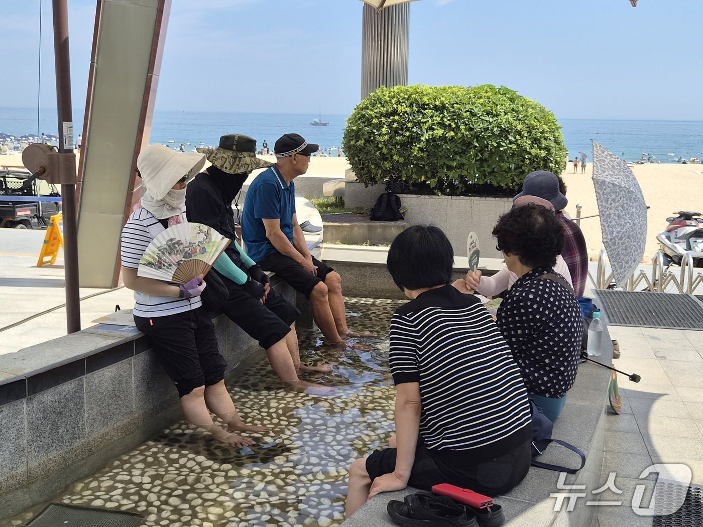 본문 이미지 - 부산 해운대해수욕장 온천족욕탕을 찾은 시민들이 바다를 바라보며 온천족욕을 즐기고 있다. 2026.7.26/뉴스1 ⓒ News1 임순택 기자