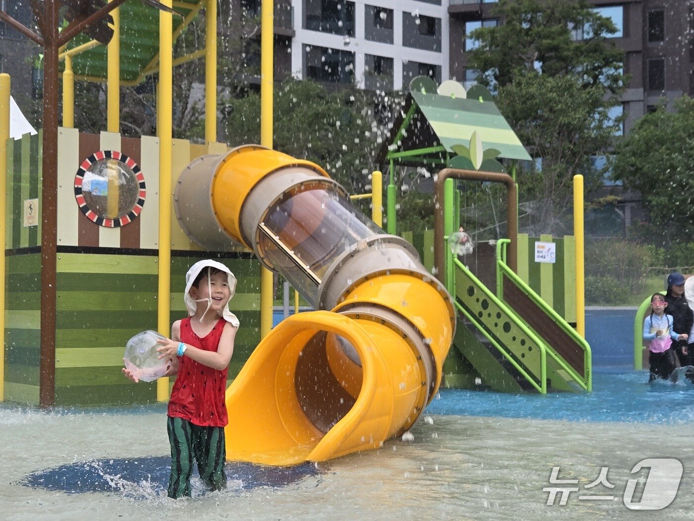 본문 이미지 - 27일 서울 서초구 원페를라 어린이공원 물놀이장에서 흰 모자를 쓴 7세 어린이가 물놀이를 즐기고 있다. 2026.7.27 ⓒ 뉴스1 김범수 기자 