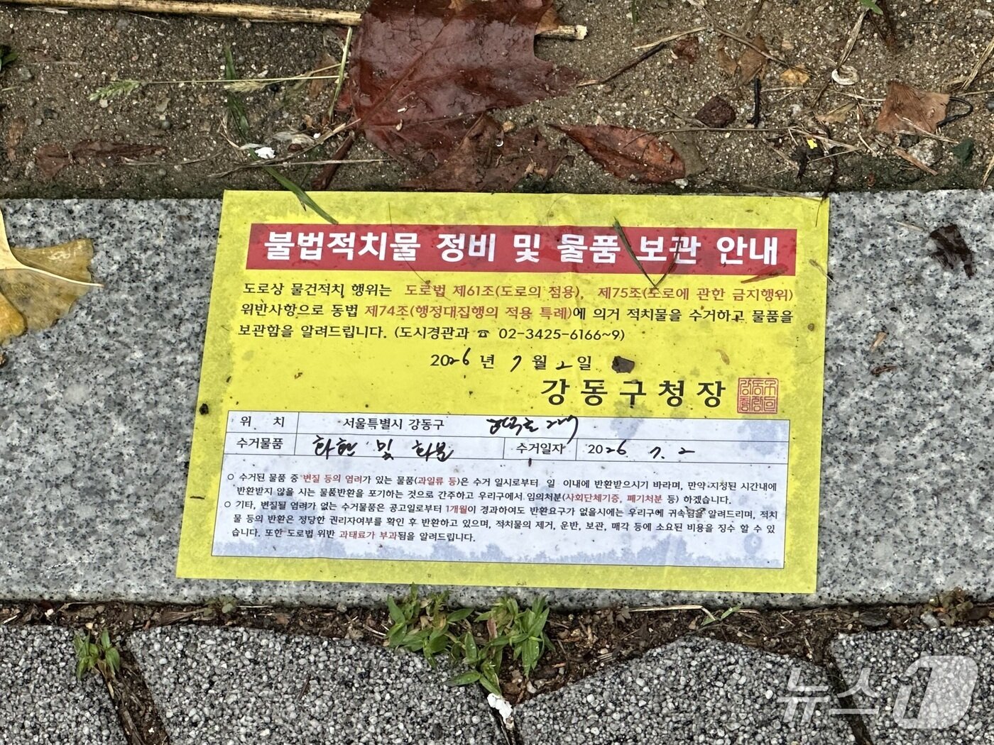 본문 이미지 - 서울 강동구 배재고등학교 앞에 세워진 화환이 전날(2일) 수거된 뒤 불법적치물 정비 및 물품보관 안내장이 바닥에 붙여진 모습. 2026.7.3 ⓒ 뉴스1 강서연 기자