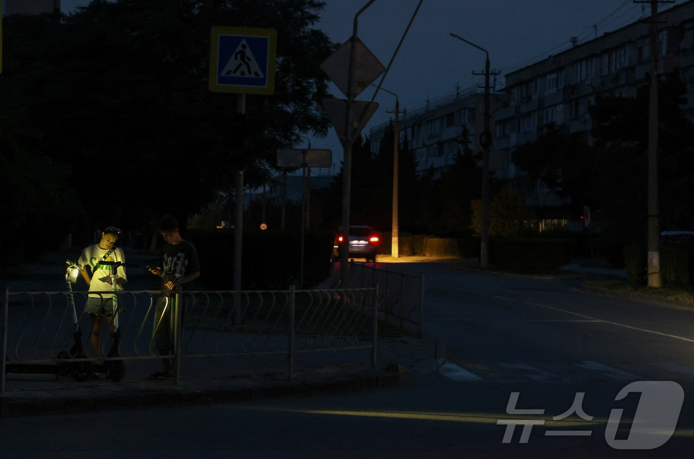 (로이터=뉴스1) 윤다정 기자 = 6월 30일(현지시간) 러시아가 점령한 크림반도 휴양 도시 예프파토리야에서 청소년들이 정전으로 어두워진 거리에 서 있다. 2026.06.30.ⓒ …