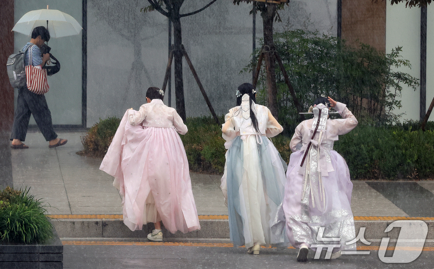 (서울=뉴스1) 이호윤 기자 = 소나기가 쏟아진 5일 서울 종로구 광화문광장에서 외국인 관광객들이 한복을 입고 비를 피하고 있다. 2026.7.5/뉴스1