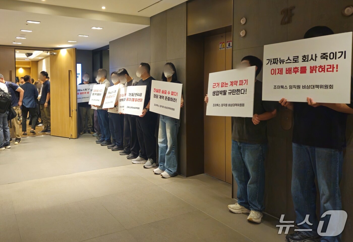본문 이미지 - 10일 기자회견장 앞에 조이웍스 임직원들이 손에 팻말을 들고 있다. ⓒ 뉴스1 박혜연 기자