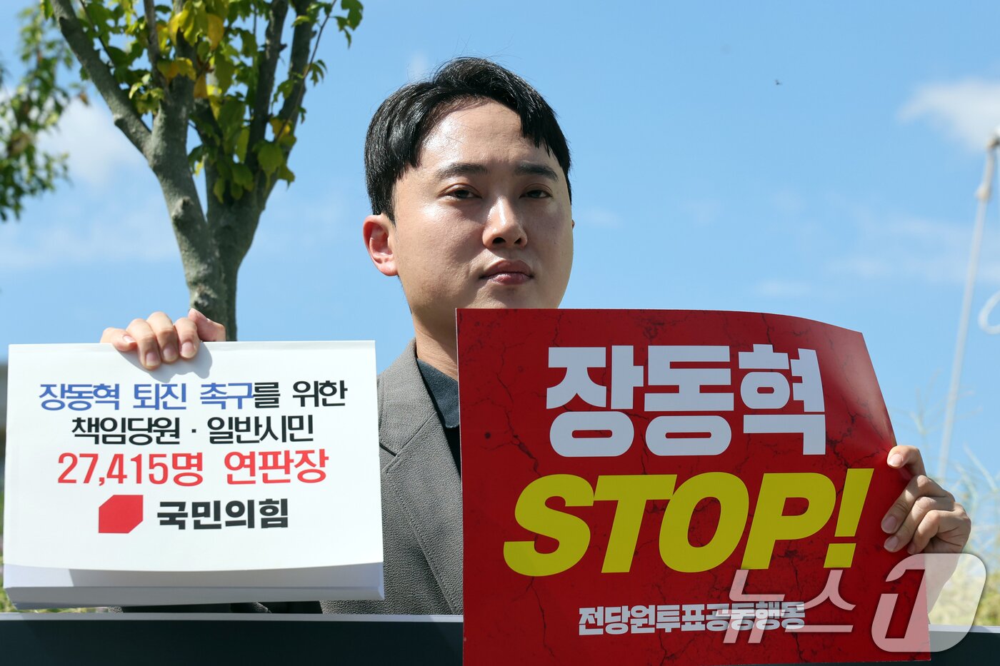 본문 이미지 - 박인규 국민의힘 책임당원이 11일 오후 서울 여의도 국회 앞에서 장동혁 대표 퇴진 촉구를 위한 책임당원·일반시민 연판장을 들어보고이고 있다. 2026.8.11 ⓒ 뉴스1 황기선 기자