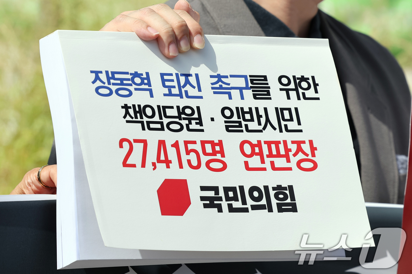 (서울=뉴스1) 황기선 기자 = 박인규 국민의힘 책임당원이 11일 오후 서울 여의도 국회 앞에서 장동혁 대표 퇴진 촉구를 위한 책임당원·일반시민 연판장을 들어보고이고 있다. 202 …
