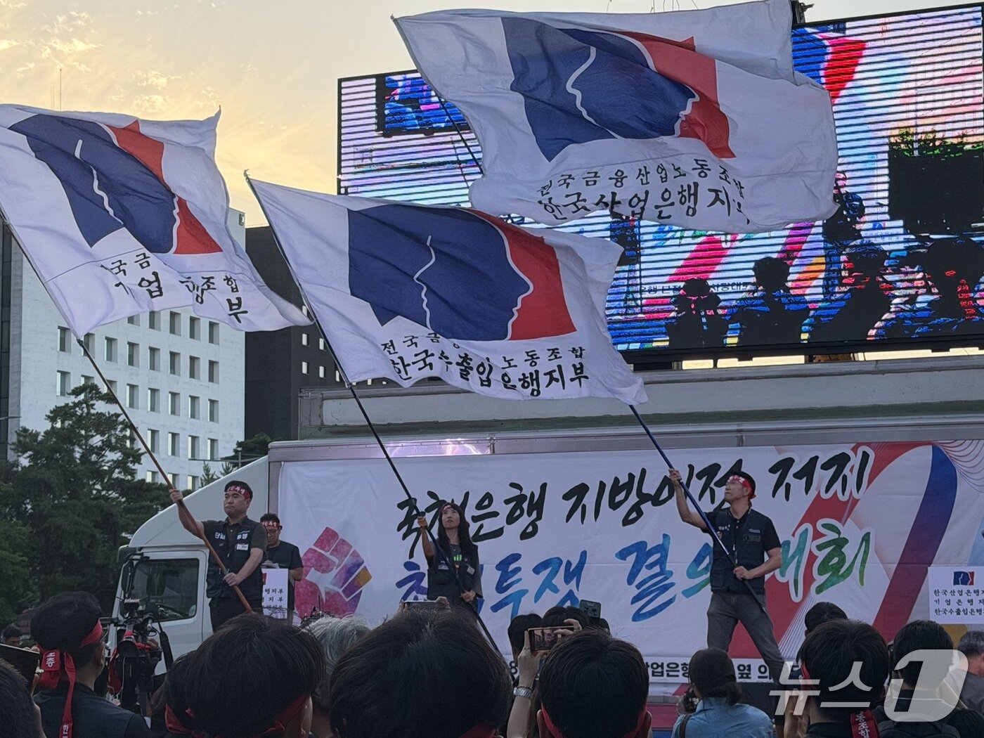 본문 이미지 - 3대 국책은행 노조 위원장들이 11일 서울 영등포구 여의도 산업은행 본점 인근에서 지방 이전 추진에 반대하는 집회에 참석해 깃발을 흔들고 있다.ⓒ News1 윤수희 기자
