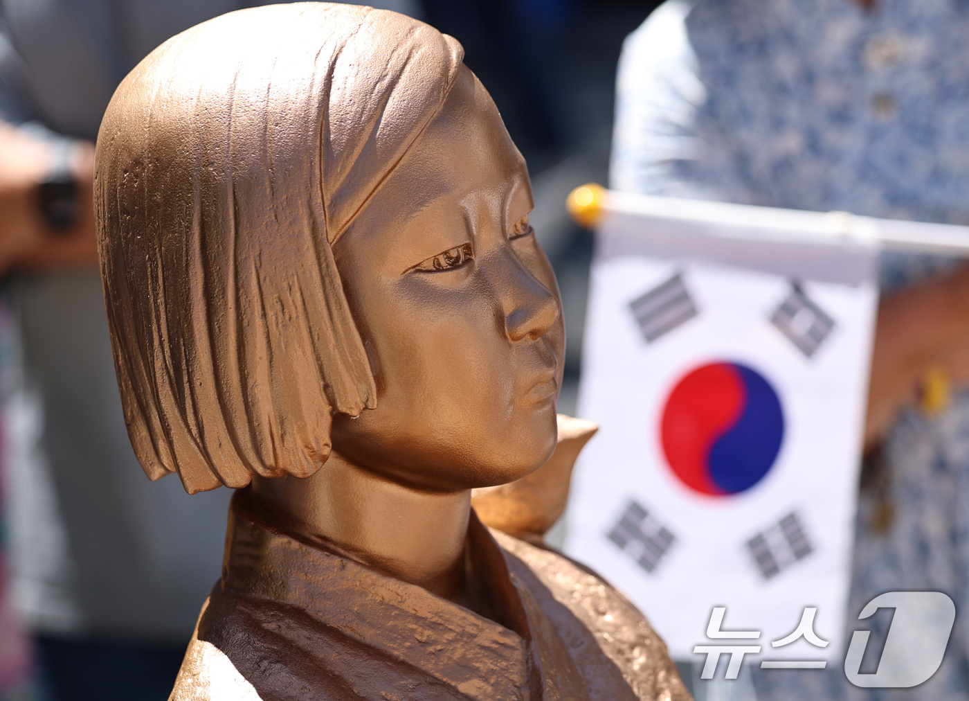 (서울=뉴스1) 구윤성 기자 = 12일 서울 종로구 옛 주한일본대사관 앞에서 열린 제14차 세계일본군 '위안부' 기림의 날 맞이 세계연대집회에서 태극기를 든 한 참가자가 평화의 소 …
