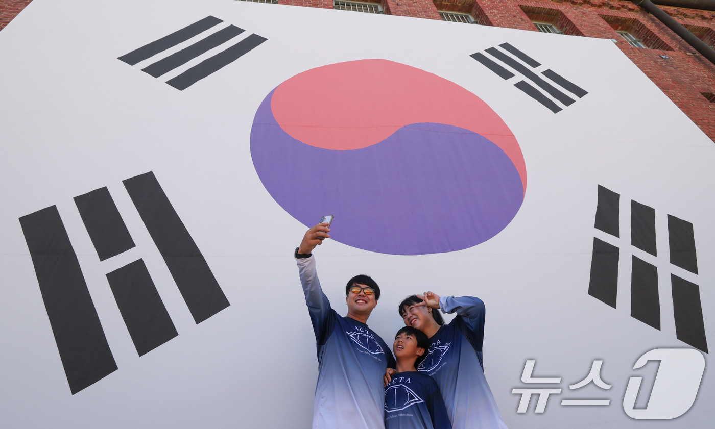 (서울=뉴스1) 이종수 기자 = 제81주년 광복절을 이틀 앞둔 13일 서울 서대문구 서대문형무소역사관을 찾은 시민들이 대형 태극기 앞에서 기념사진을 찍고 있다. 2026.8.13/ …