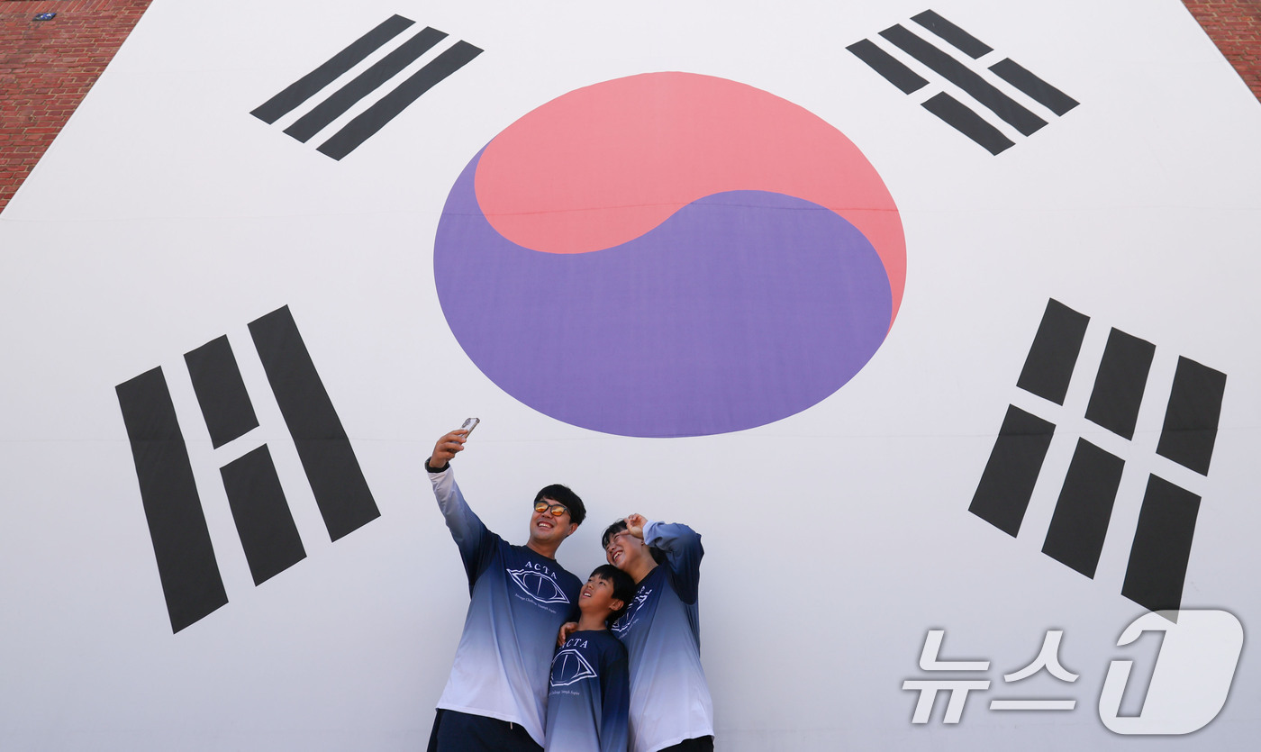 (서울=뉴스1) 이종수 기자 = 제81주년 광복절을 이틀 앞둔 13일 서울 서대문구 서대문형무소역사관을 찾은 시민들이 대형 태극기 앞에서 기념사진을 찍고 있다. 2026.8.13/ …