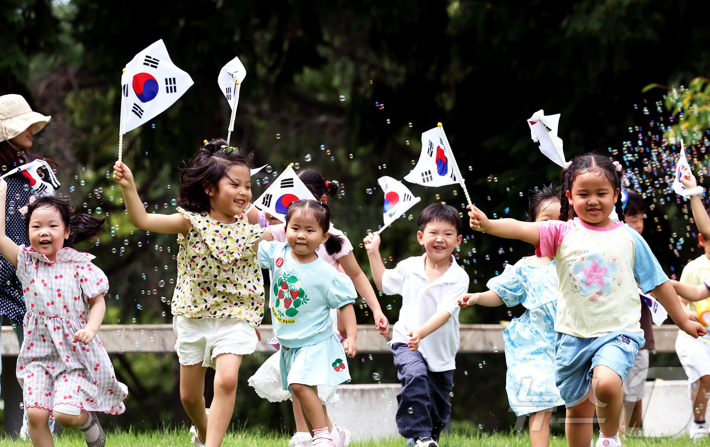 (광주=뉴스1) = 제 81주년 광복절을 이틀 앞둔 13일 전남광주통합특별시 북구청 직장어린이집 아이들이 용봉동 전남대학교 캠퍼스 잔디광장에서 태극기를 흔들며 야외 활동을 하고 있 …