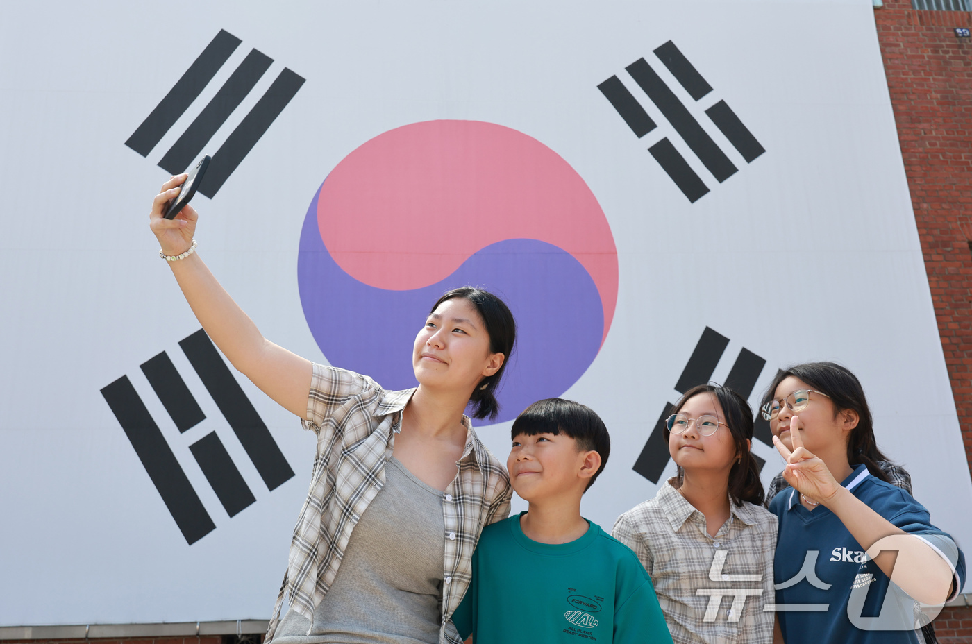 (서울=뉴스1) 이호윤 기자 = 제81주년 광복절을 하루 앞둔 14일 서울 서대문구 서대문형무소역사관 대형 태극기 앞에서 학생들이 기념촬영을 하고 있다. 2026.8.14/뉴스1