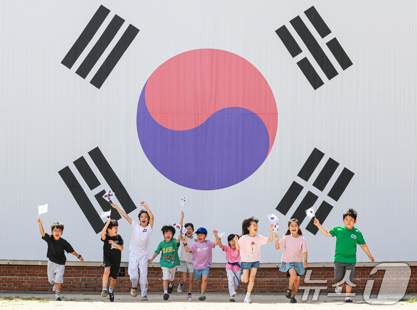 (서울=뉴스1) 이호윤 기자 = 제81주년 광복절을 하루 앞둔 14일 서울 서대문구 서대문형무소역사관 대형 태극기 앞에서 어린이들이 직접 만든 태극기를 흔들며 힘차게 뛰고 있다. …