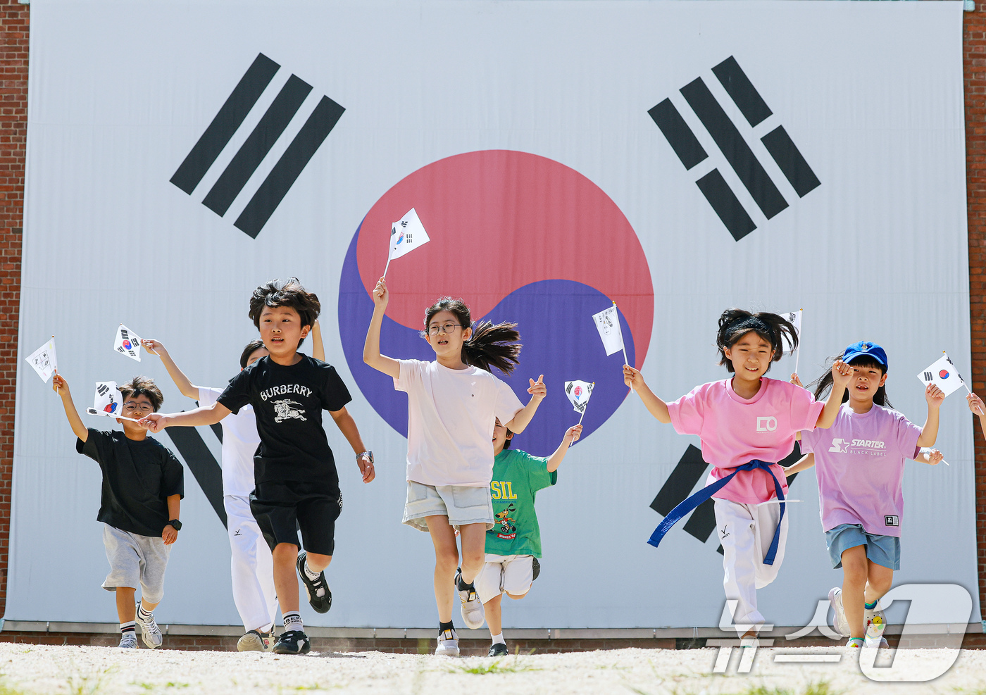 (서울=뉴스1) 이호윤 기자 = 제81주년 광복절을 하루 앞둔 14일 서울 서대문구 서대문형무소역사관 대형 태극기 앞에서 어린이들이 직접 만든 태극기를 흔들며 힘차게 뛰고 있다. …