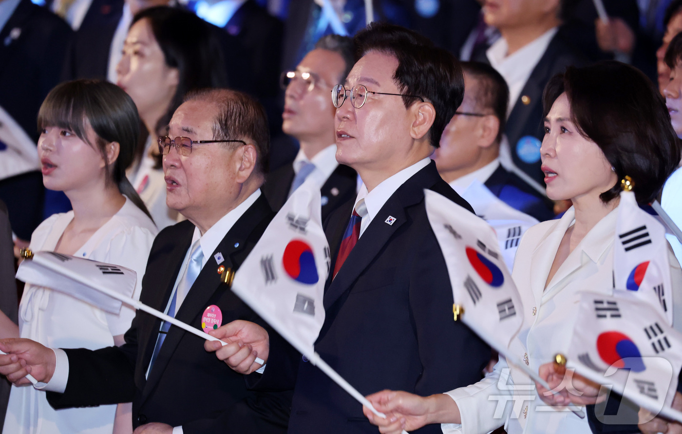 (서울=뉴스1) 이재명 기자 = 이재명 대통령과 김혜경 여사가 15일 서울 종로구 세종문화회관에서 열린 제81주년 광복절 경축식에서 광복절 노래를 제창하며 태극기를 흔들고 있다. …