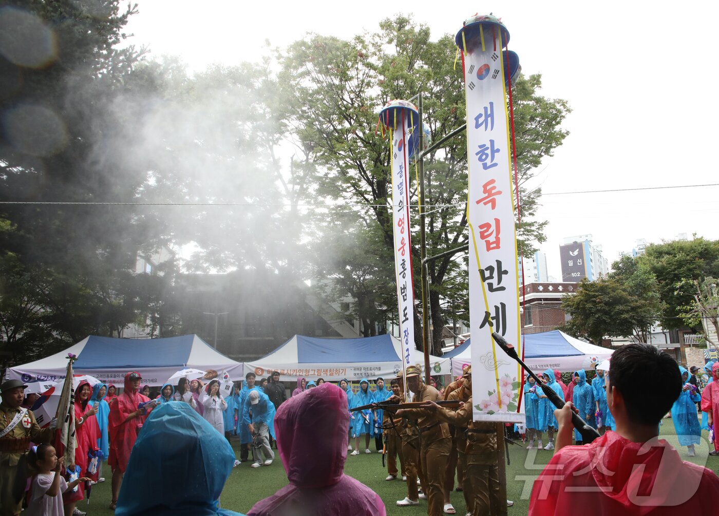 본문 이미지 - 15일 오전 10시 전남광주 광산구 월곡동에서 81주년 광복절을 맞아 열린 봉오동 전투 재현 행사에서 물줄기를 맞고 터진 박. 두 개의 현수막에는 '대한 독립 만세'와 '불멸의 영웅 홍범도 장군'이란 글귀가 새겨져 있다. 2026.8.15 ⓒ 뉴스1 안재영 기자