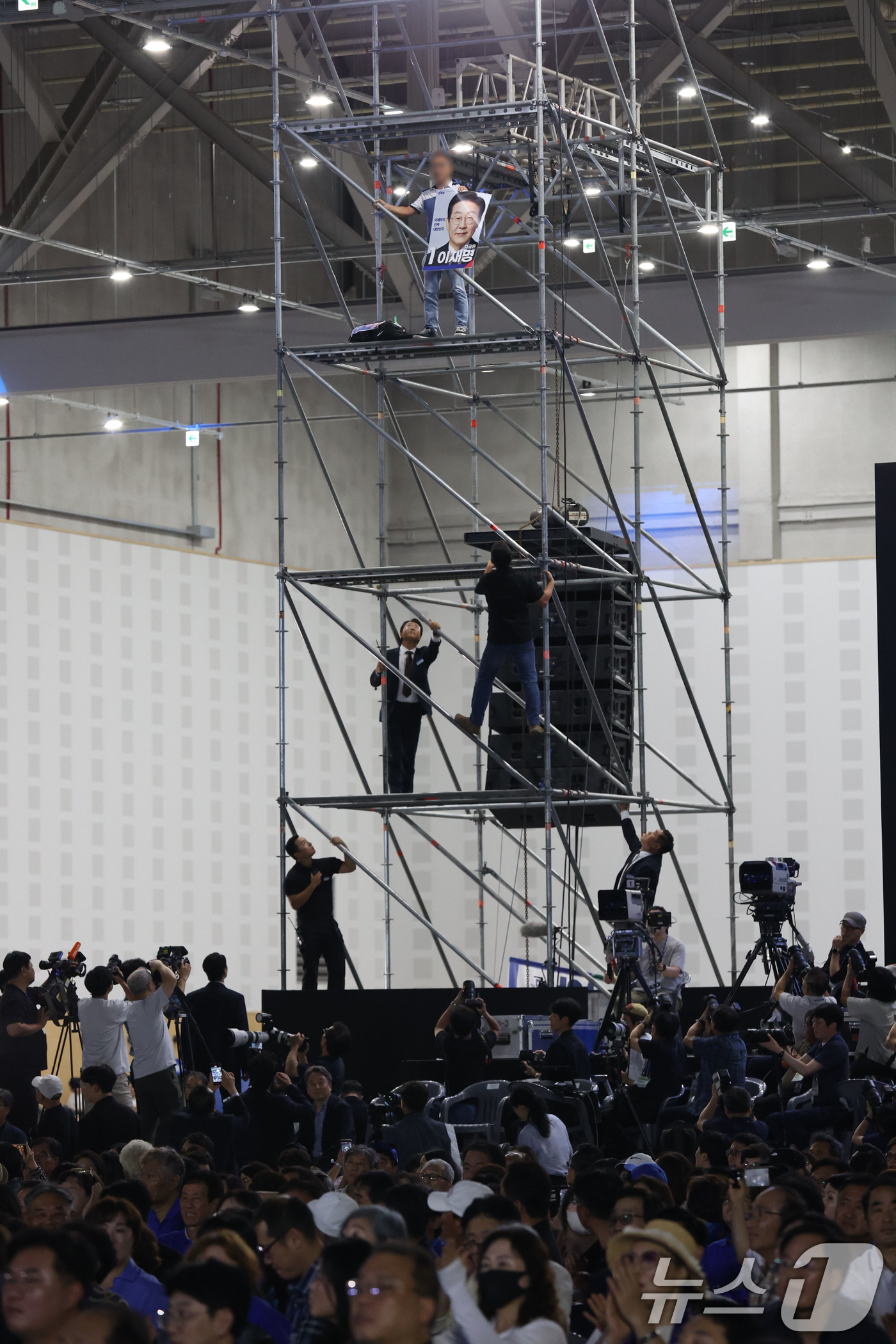 (대전=뉴스1) 황기선 기자 = 17일 오후 대전 유성구 DCC대전컨벤션센터에서 열린 '제3차 정기전국당원대회'에서 한 참석자가 비계 구조물에 올라가 소동을 벌이고 있다. (공동취 …