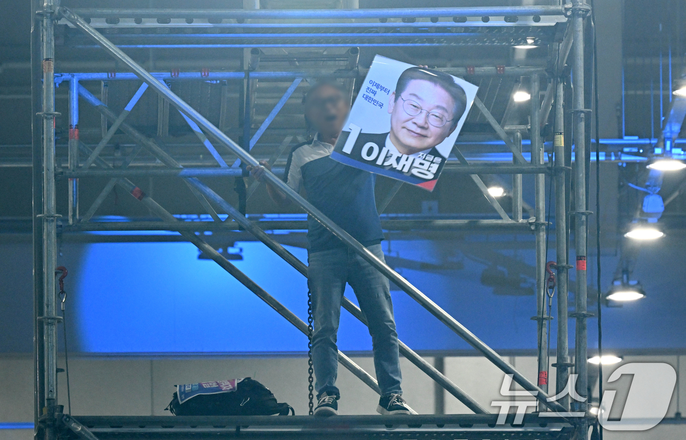 (대전=뉴스1) 황기선 기자 = 17일 대전 유성구 대전컨벤션센터 제2전시장에서 열린 더불어민주당 제3차 정기전국당원대회에서 한 참석자가 조명탑에 올라 난동을 부리고 있다. (공동 …