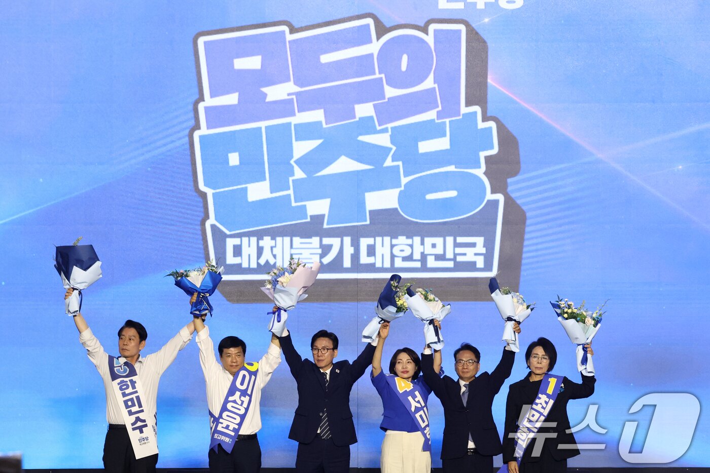 본문 이미지 - 더불어민주당 김민석 신임 당대표와 최고위원들이 17일 오후 대전 유성구 DCC대전컨벤션센터에서 열린 '더불어민주당 제3차 정기전국당원대회'에서 손을 들어 인사하고 있다. 왼쪽부터 한민수, 이성윤, 김 대표, 서미화, 박선원, 최민희. 2026.8.17 ⓒ 뉴스1 황기선 기자