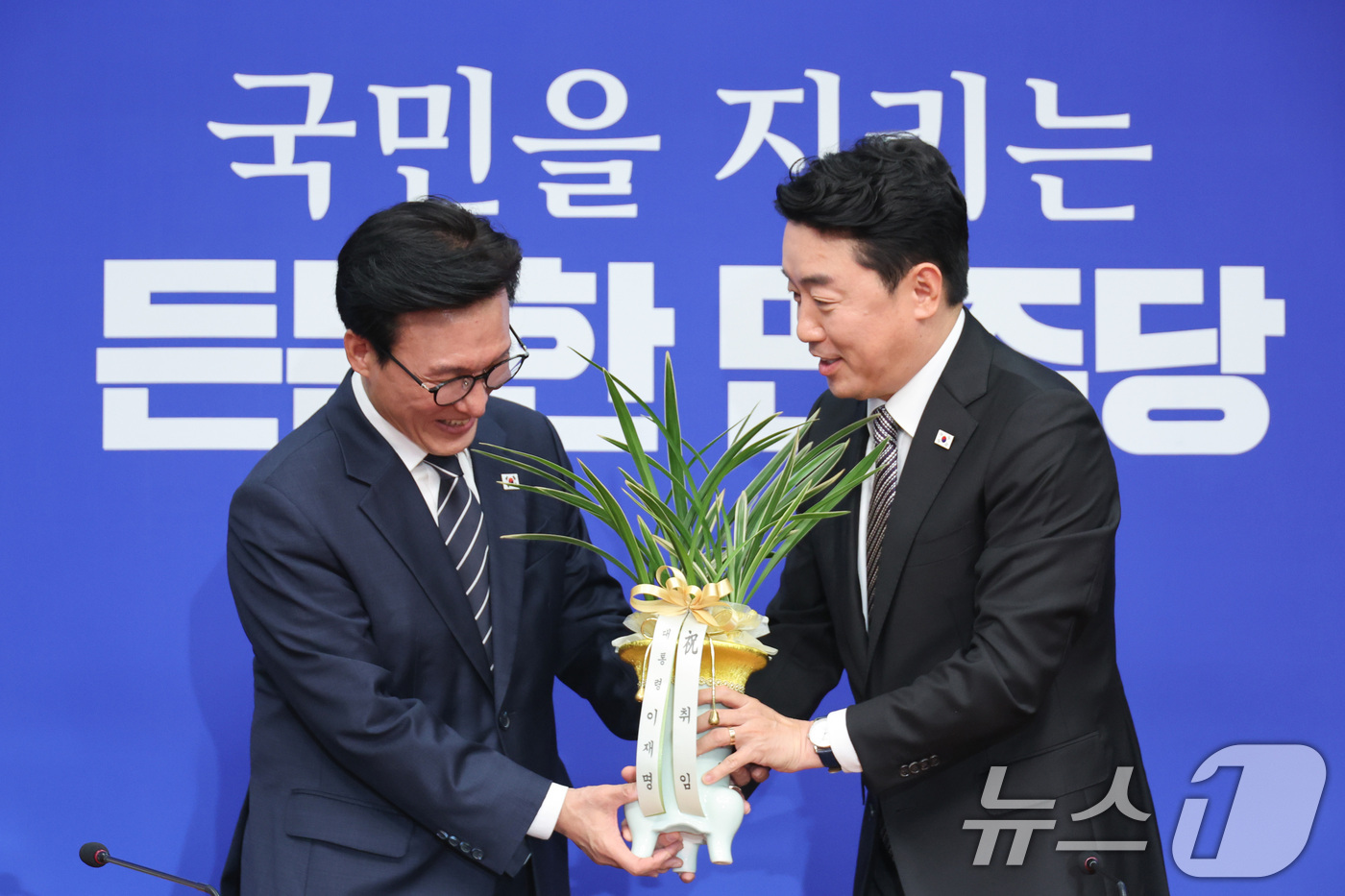 (서울=뉴스1) 신웅수 기자 = 김민석 더불어민주당 대표가 18일 서울 여의도 국회를 찾은 강훈식 대통령 비서실장으로부터 이재명 대통령의 당선 축하난을 전달받고 있다. 2026.8 …
