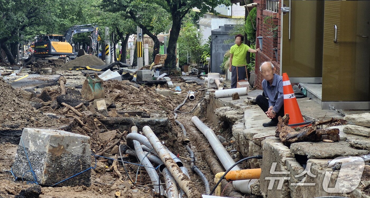 본문 이미지 - 18일 극한 호우로 유실된 경남 통영시 봉평동 용화사 인근 한 도로에서 복구 작업이 진행돼 주민들이 이를 지켜보고 있다. 2026.8.18 ⓒ 뉴스1 윤일지 기자