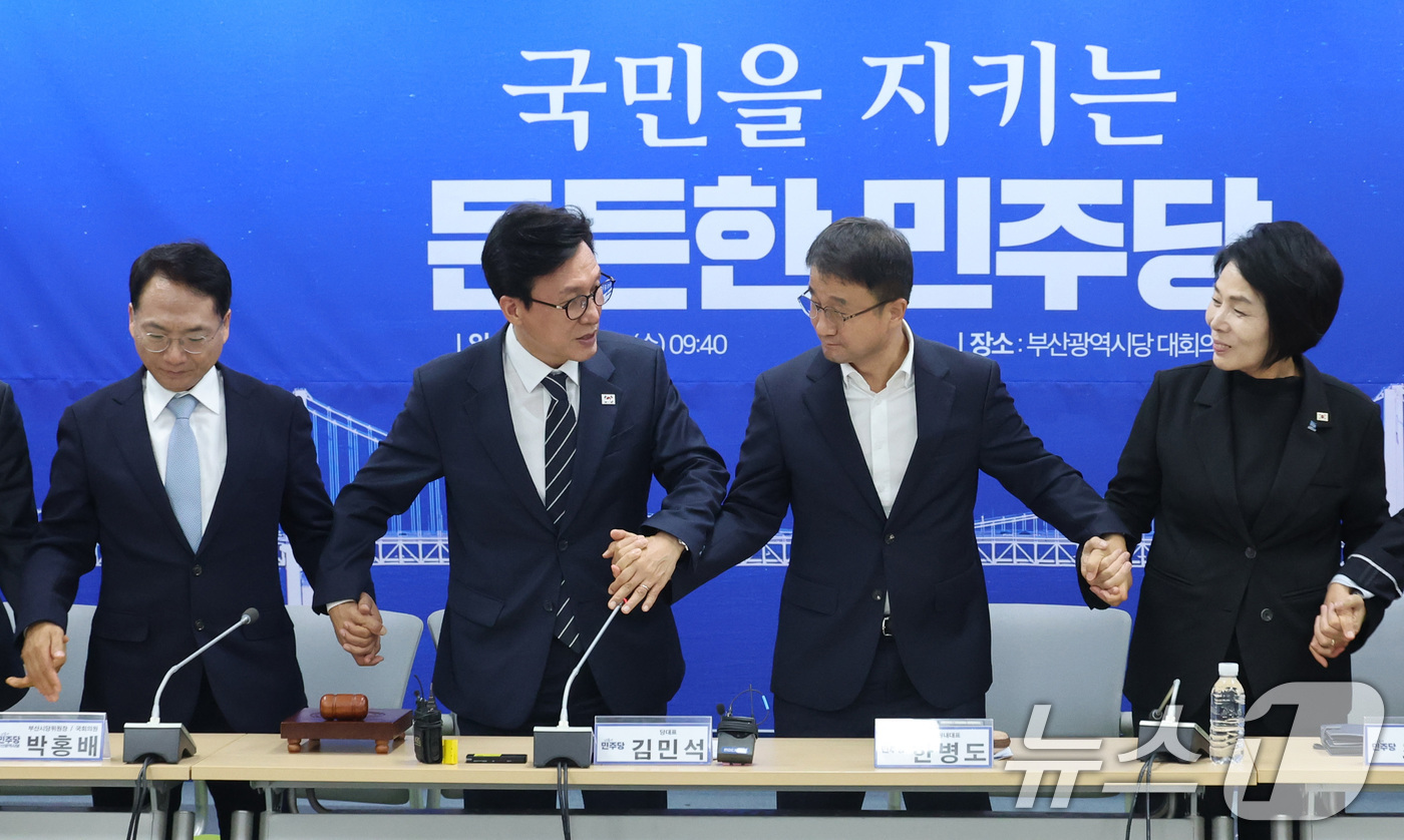 (부산=뉴스1) 신웅수 기자 = 김민석 더불어민주당 대표가 19일 부산 동구 민주당 부산시당에서 열린 현장 최고위원회의에서 한병도 원내대표, 최고위원들의 손을 잡고 있다. 2026 …