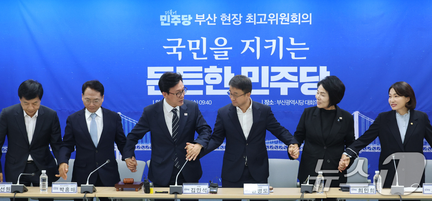 (부산=뉴스1) 신웅수 기자 = 김민석 더불어민주당 대표가 19일 부산 동구 민주당 부산시당에서 열린 현장 최고위원회의에서 한병도 원내대표, 최고위원들의 손을 잡고 있다. 2026 …