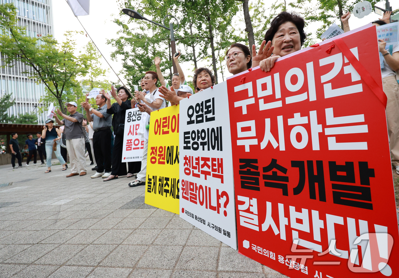 (서울=뉴스1) 이호윤 기자 = 용산 주민들이 19일 서울 용산구 한마음공원에서 열린 '용산어린이정원 사수 궐기대회‘에서 피켓을 들며 용산어린이정원 일대 주택 공급 개발을 반대하고 …