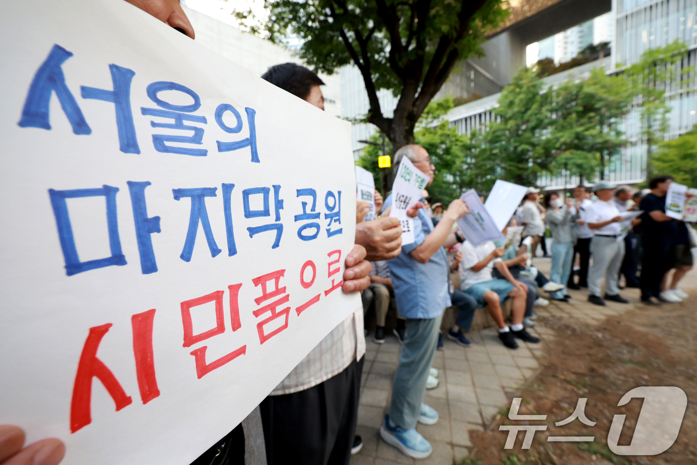 (서울=뉴스1) 이호윤 기자 = 용산 주민들이 19일 서울 용산구 한마음공원에서 열린 '용산어린이정원 사수 궐기대회‘에서 피켓을 들며 용산어린이정원 일대 주택 공급 개발을 반대하고 …