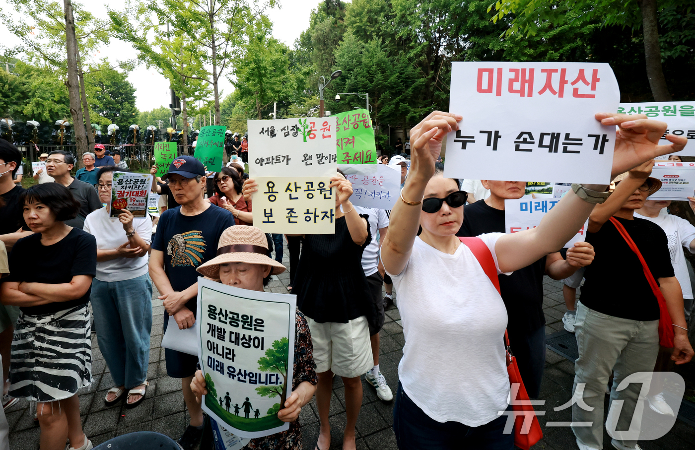(서울=뉴스1) 이호윤 기자 = 용산 주민들이 19일 서울 용산구 한마음공원에서 열린 '용산어린이정원 사수 궐기대회‘에서 피켓을 들며 용산어린이정원 일대 주택 공급 개발을 반대하고 …