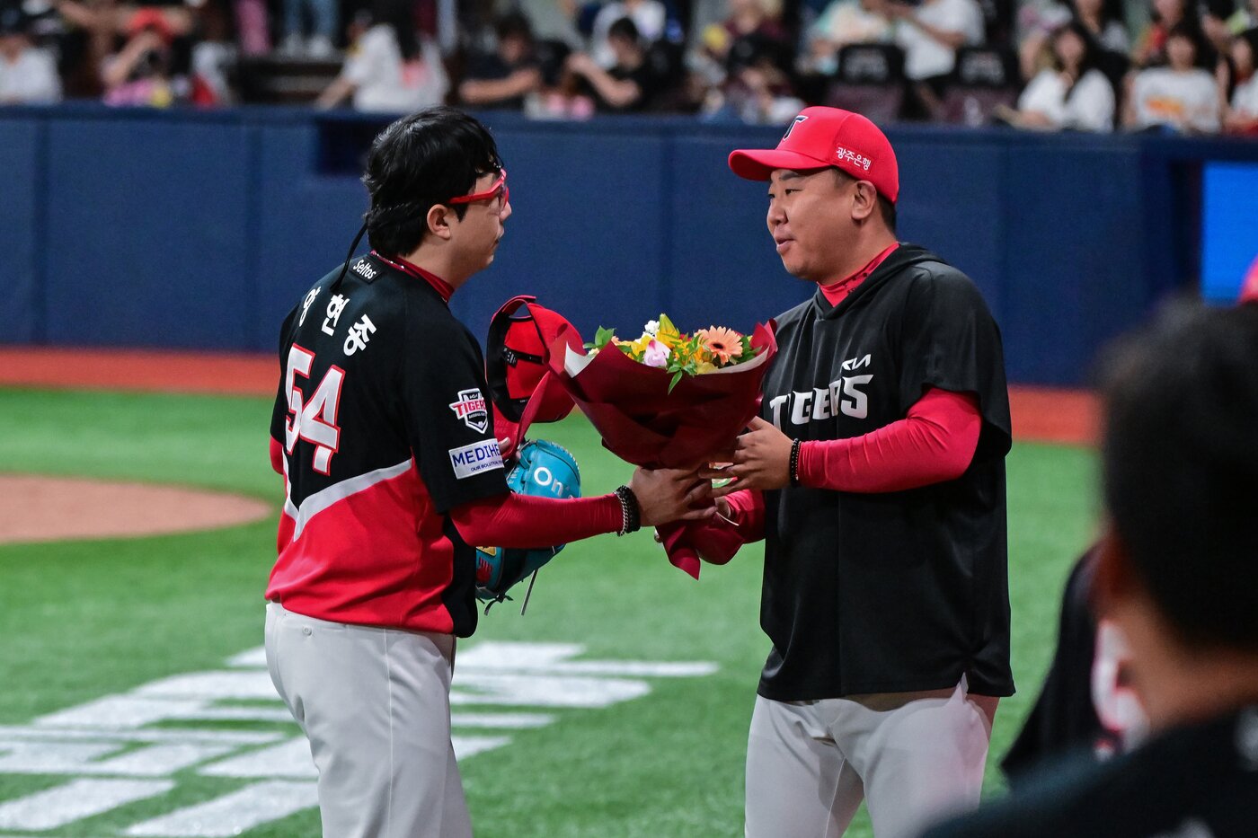 본문 이미지 - KIA 양현종이 21일 서울 고척 스카이돔에서 열린 2026 신한 SOL KBO리그 키움 히어로즈전에서 13시즌 연속 100이닝을 달성한 뒤 이범호 감독에게 축하 꽃다발을 받고 있다. (KIA 제공)