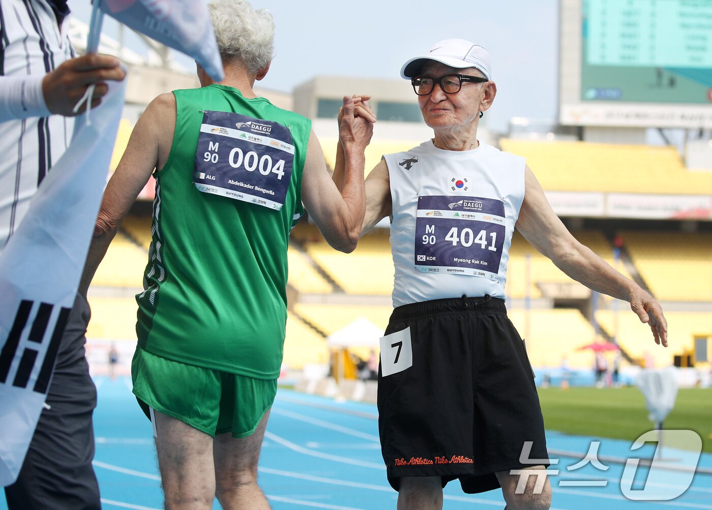 본문 이미지 - 23일 오전 대구스타디움에서 열린 '대구세계마스터즈육상경기대회' 남자 90세 100m 달리기 준결승에 출전한 국내 최고령 참가자 김명락 씨(90)가 결승선을 통과한 뒤 함께 달린 알제리 선수와 하이파이브 나누며 축하하고 있다. ⓒ 뉴스1 공정식 기자