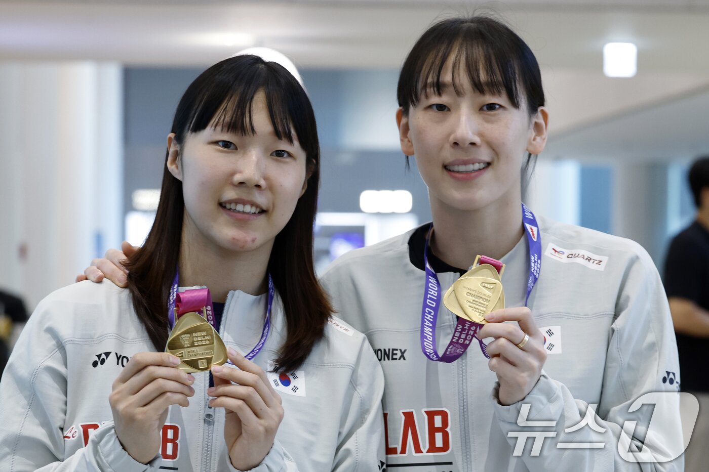 본문 이미지 - 세계선수권대회 여자복식 우승을 차지한 이소희와 백하나가 25일 오전 인천국제공항을 통해 귀국해 메달을 들어 보이고 있다. 세계랭킹 3위 이소희-백하나 조는 23일(한국시간) 인도 뉴델리에서 열린 2026 세계배드민턴연맹(BWF) 세계선수권대회 여자복식 결승에서 세계랭킹 1위 류성수-탄닝(중국) 조를 51분 만에 게임 스코어 2-0(21-15 21-15)으로 제압해, 1995년 길영아-장혜옥 조의 우승 이후 무려 31년 만에 세계선수권 여자복식 금메달을 수확했다. ⓒ 뉴스1 박정호 기자