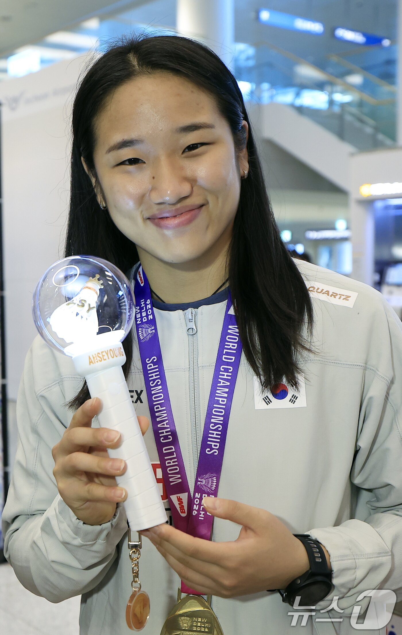 본문 이미지 - 2026 세계배드민턴연맹(BWF) 세계선수권대회 여자 단식을 제패한 안세영이 25일 오전 인천국제공항을 통해 귀국, 팬카페 회원들이 제작해 선물한 자신의 응원봉을 들어 보이고 있다.  2026.8.25 ⓒ 뉴스1 박정호 기자