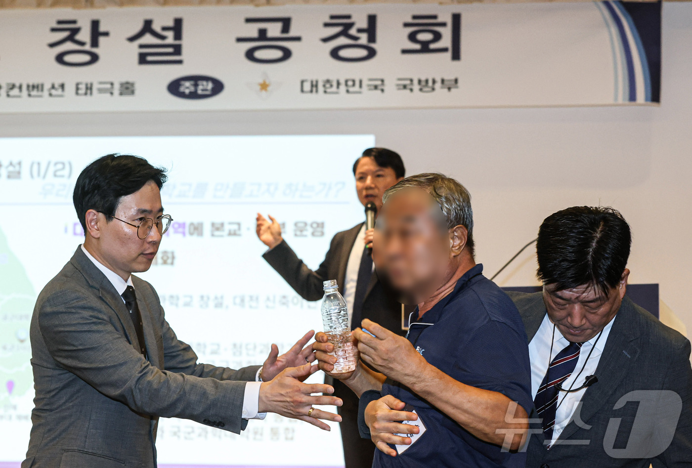 (서울=뉴스1) 최지환 기자 = 26일 오후 서울 용산구 국방컨벤션에서 열린 국군사관학교 창설 공청회에서 한 참석자가 발언하고 있는 김홍철 국방부 정책실장에게 생수병을 든 채 다가 …
