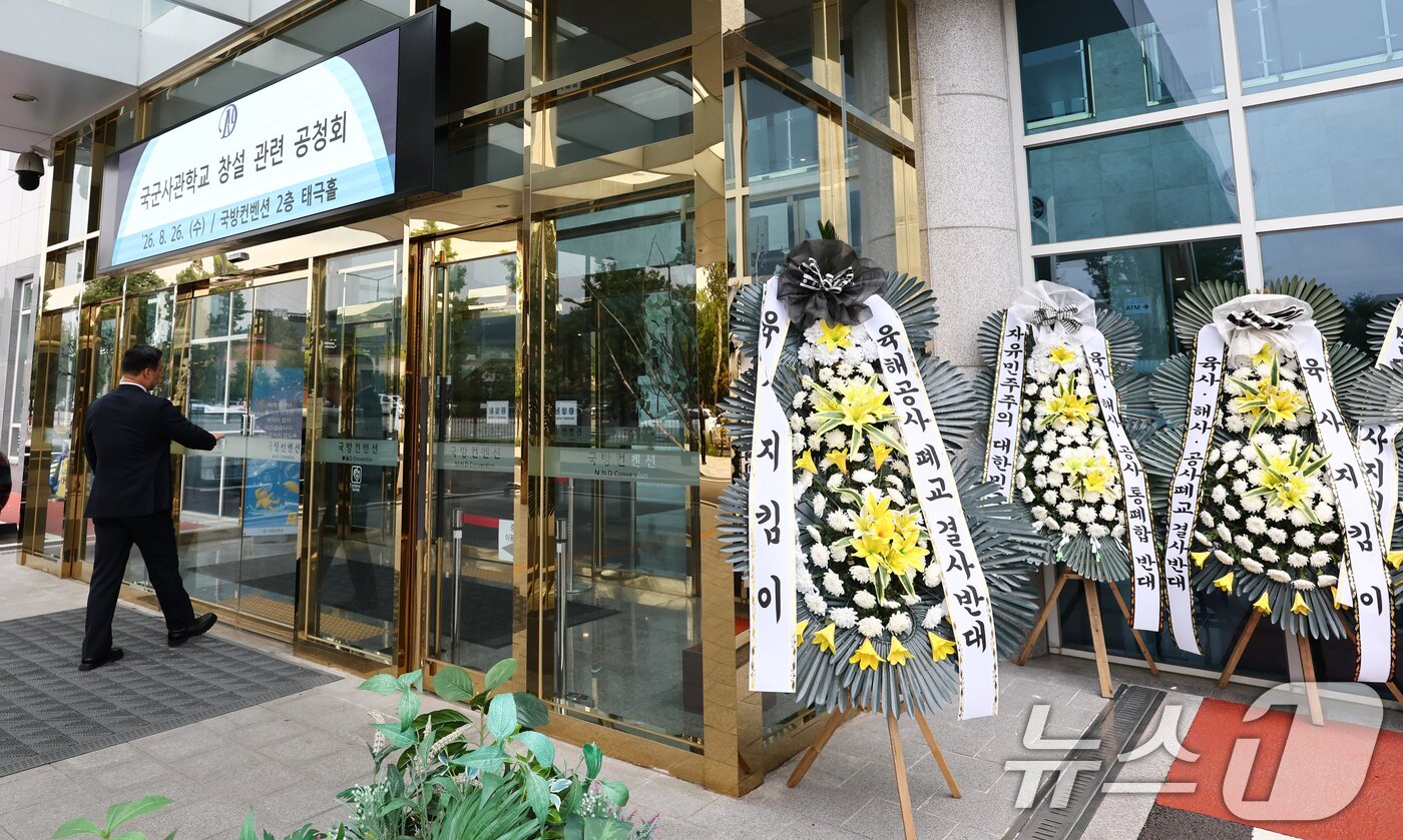 본문 이미지 - 26일 오후 국군사관학교 창설 공청회가 열린 서울 용산구 국방컨벤션 앞에 국군사관학교 창설 반대 화환이 설치되어 있다. 2026.8.26 ⓒ 뉴스1 최지환 기자